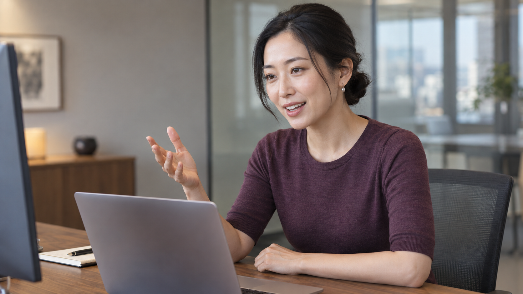 PCの画面を見ながら、手振りを交えて説明する女性。